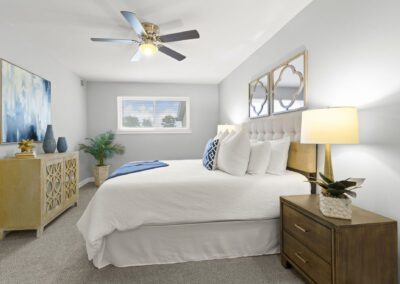 A serene bedroom scene showcasing a ceiling fan and a well-arranged bed, emphasizing relaxation and comfort