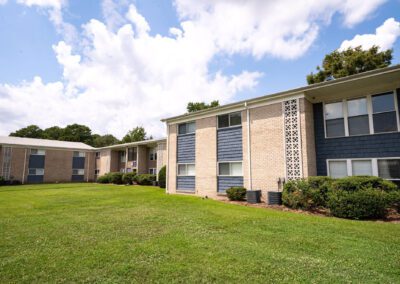 Exterior view of an apartment building surrounded by lush grass and trees, showcasing a serene urban environment